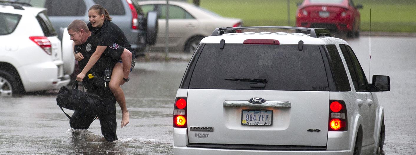 An officer carries a student from a flooded vehicle.